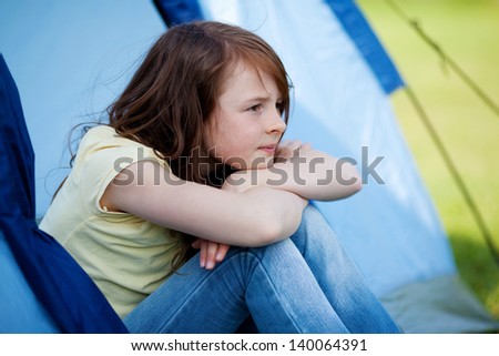 Thoughtful little girl looking away while sitting in tent