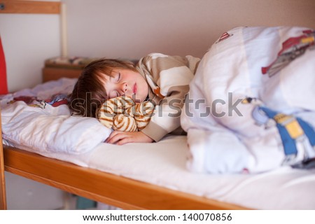 Cute little boy sleeping on bunk bed at hole