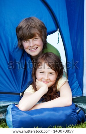 Portrait of young brother and sister lying in tent at forest