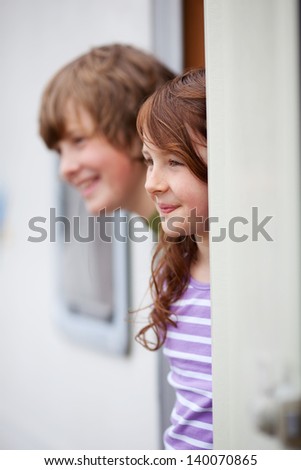 Young brother and sister looking away while at doorway of RV