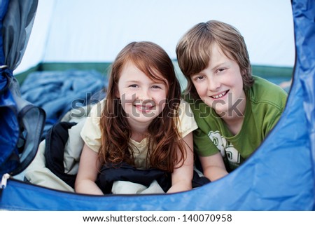 Portrait of young brother and sister lying in tent