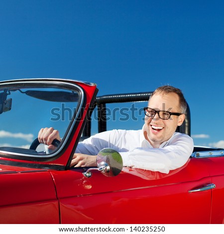 Happy man riding a red convertible car over the bright blue sky