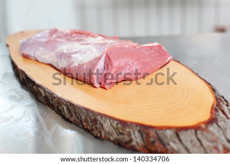 Fresh meat on display over a wooden meat board in a butcher shop