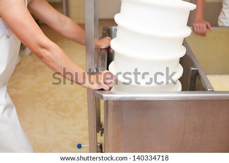 Workers around the Vat-Machine in the Cheesemaking shop with several plastic colanders