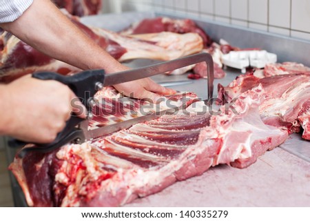 A butcher cuts a fresh beef carcass in a close up image