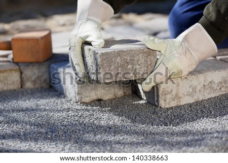 Close up shit of construction worker paving the brick road