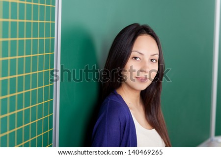 female student leaning against blackboard at university classroom