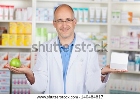 pharmacist showing apple and medicin in his hands