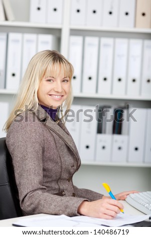 Portrait of beautiful businesswoman writing on document at office desk