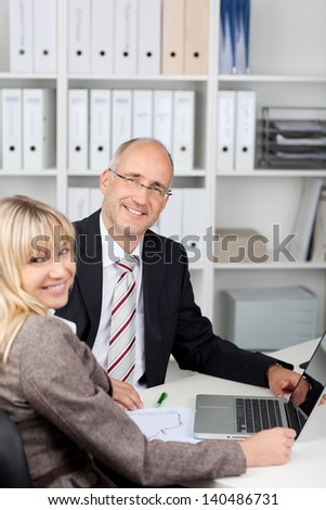 female and mal coworker looking back from laptop