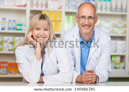 Portrait of male and female pharmacists leaning on pharmacy counter