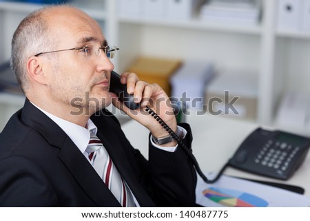 serious manager using the phone at his office desk