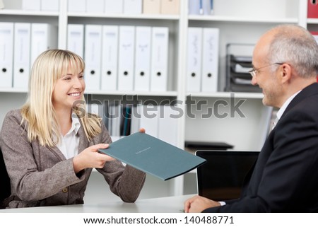 Female candidate giving application file to businessman in office