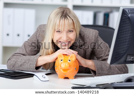 Portrait of businesswoman with piggy bank at desk in office