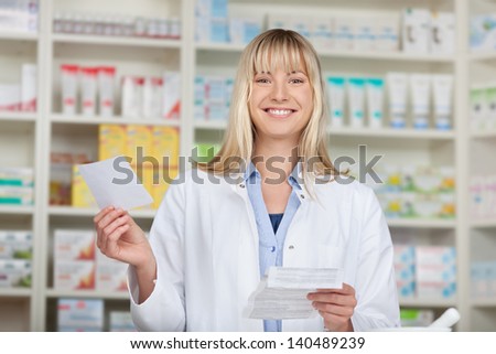 Portrait of young female pharmacist holding prescription papers in pharmacy
