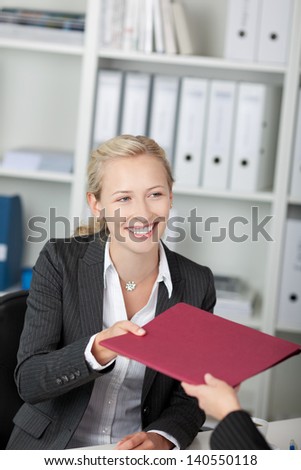 Happy young businesswoman receiving application map at office desk
