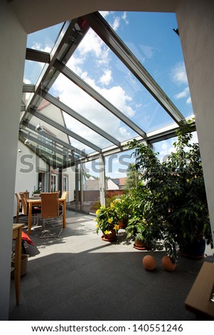 View of patio covered with glass with furniture and plants in it