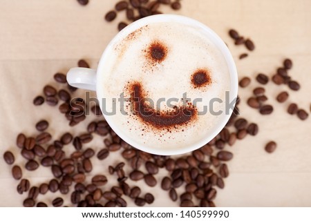 Closeup Of Smiley Face In Cappuccino With Coffee Beans On Table At Cafe