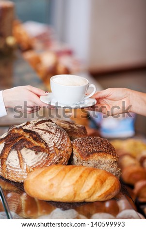 Closeup female bakery worker serving cappuccino