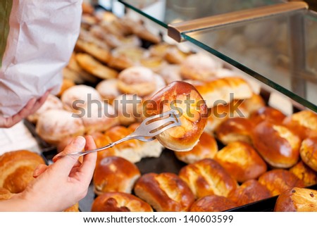 Closeup of female bakery worker\'s hands packing bread at counter