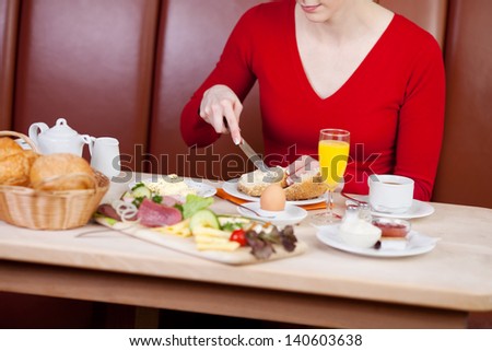 woman sitting at tablet and having breakfast in hotel