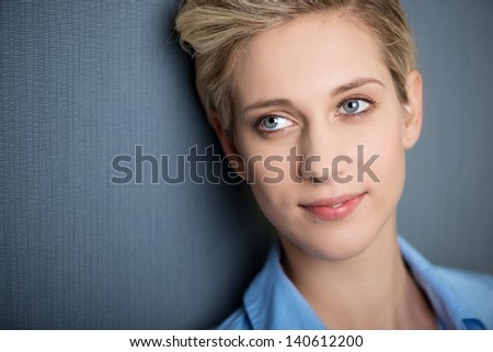 Closeup of businesswoman smiling while looking away against blue wall