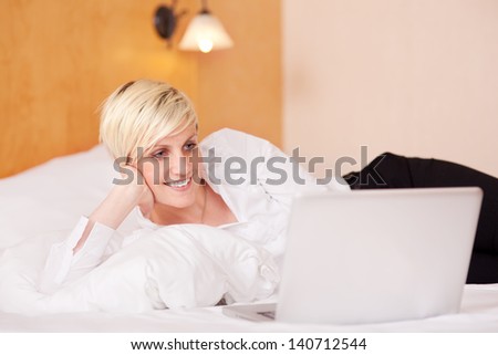 Happy businesswoman using laptop while lying on bed