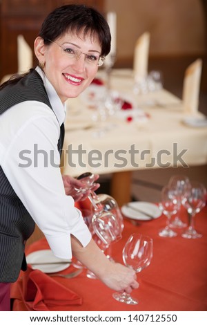 waitress setting the table at restaurant, looking up