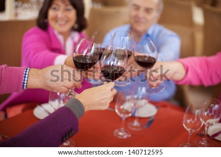 Smiling Elderly Friends Saying Cheers With Red Wine