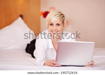 Portrait of young businesswoman with laptop while lying on bed