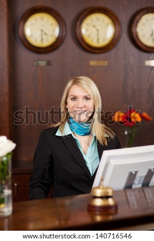 Smiling Blond Receptionist Behind The Counter In Hotel