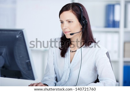 Beautiful call center agent browsing the internet on her computer