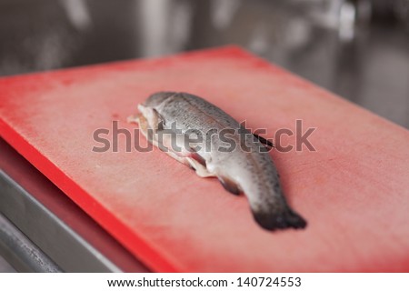 Selective focus of raw fish on chopping board at commercial kitchen