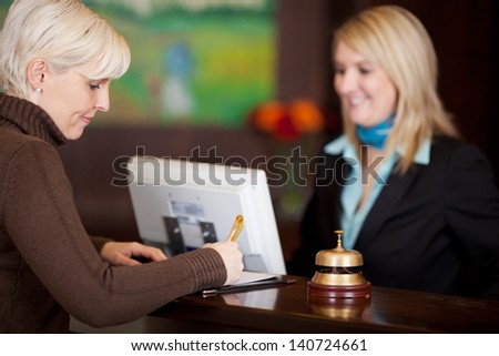 Female Guest Filling Up A Formular At Hotel Counter