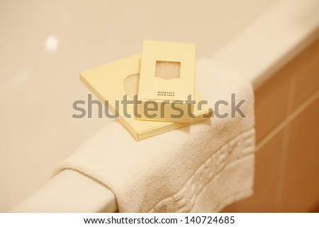 Packets of bath salt and napkin on bathtub in hotel bathroom