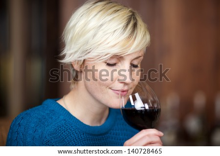 closeup portrait of young blond woman drinking red wine in restaurant
