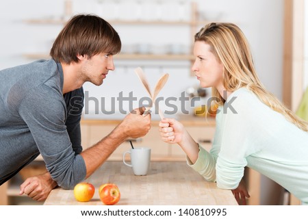 Young Couple In The Kitchen Crossing Spoons