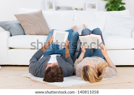 Relaxed Couple Lying On The Floor With Book And Ebook