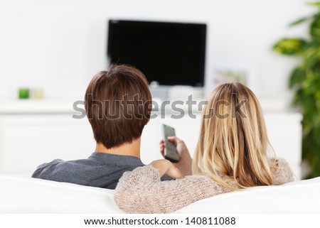 couple sitting on sofa and watching tv