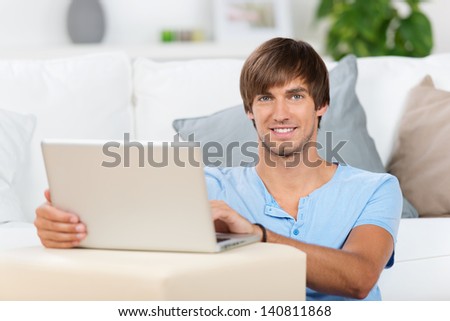 smiling man sitting at home with laptop smiling man sitting at home with laptop