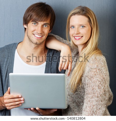 couple with laptop in front of grey wall