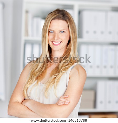 smiling blond woman in the office with folded arms