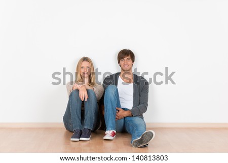 smiling couple sitting on the floor in an empty room