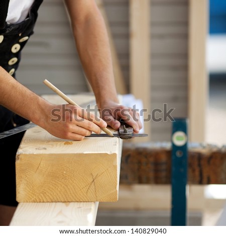 Construction worker marks a piece of wood