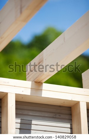 Detail of the roof beams of an unfinished roof with trees and sky in the background