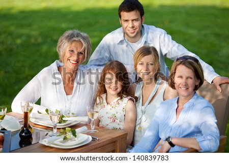 Group portrait of happy multi generation family smiling together at dining table
