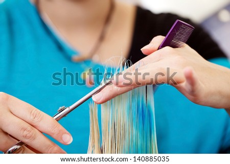 female hairdresser cutting hair tips in salon