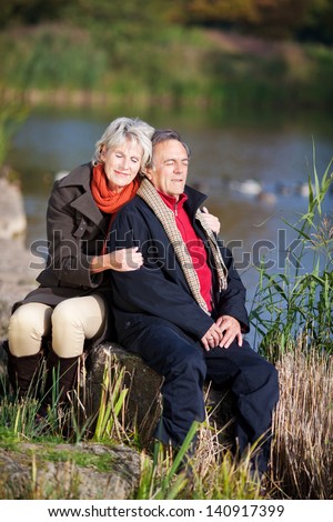 Happy senior couple enjoying the sun near a lake