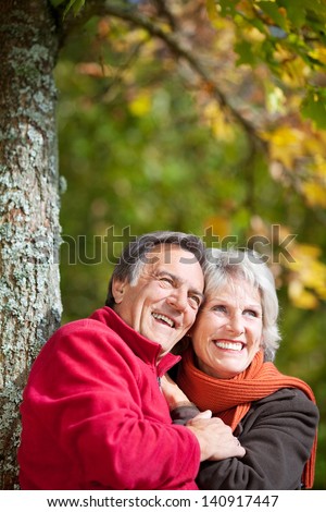 Happy old couple laughing while looking at something in the park