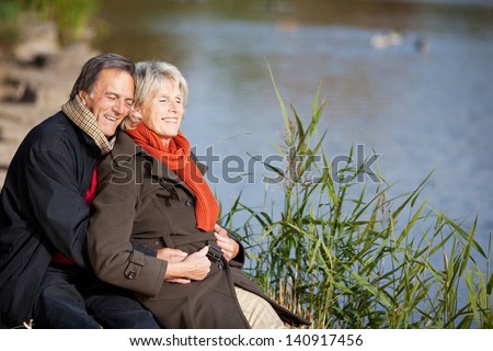A happy senior couple enjoying the sun near a lake